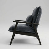 A modern lounge chair with dark charcoal gray velvet cushions and a dark wood frame, shown from a side profile against a light gray studio background.