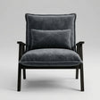 A modern armchair with dark gray velvet upholstery and a matching back cushion, supported by a dark wood frame, shown against a neutral light gray background.