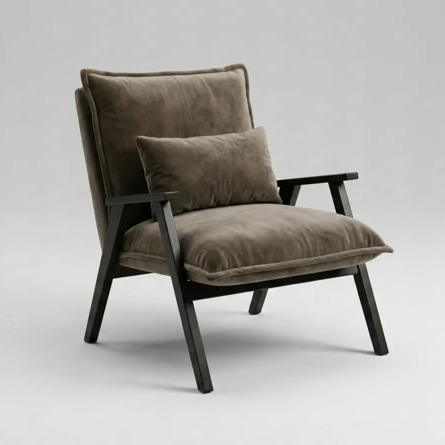 A modern accent chair with plush taupe-brown velvet cushions and a matching back pillow, supported by a dark wood frame, photographed on a seamless light gray studio background.