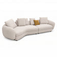 A modern curved upholstered sofa in a light beige textured fabric, featuring multiple matching back cushions and a single mustard yellow accent pillow, shown on a plain white background.