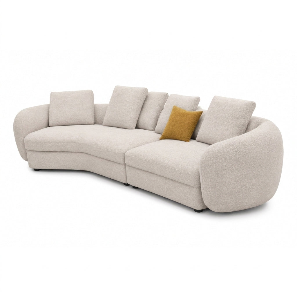 A curved modular upholstered sofa in a light beige bouclé fabric, featuring multiple back cushions and a single mustard yellow accent pillow, shown on a plain white background.
