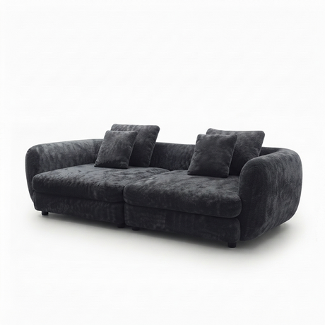 A modern curved three-seater sofa upholstered in dark charcoal gray plush velvet fabric, shown with four matching throw pillows against a plain white background.