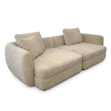 A modern sectional sofa upholstered in a textured bouclé fabric in a light beige color, featuring a chaise lounge on the left and two matching back cushions, shown against a plain white background.