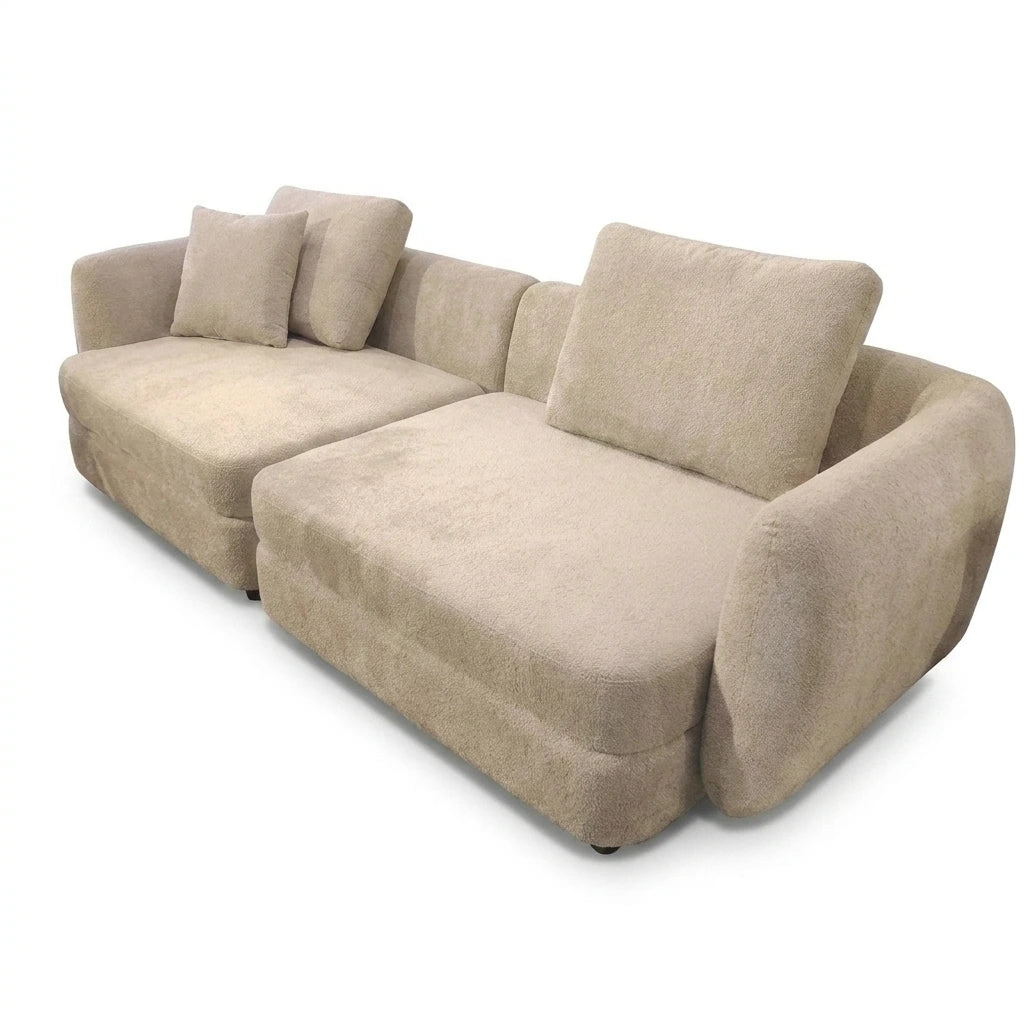 A modern beige fabric sectional sofa with a chaise lounge on the right side, featuring two matching throw pillows, shown on a plain white background.