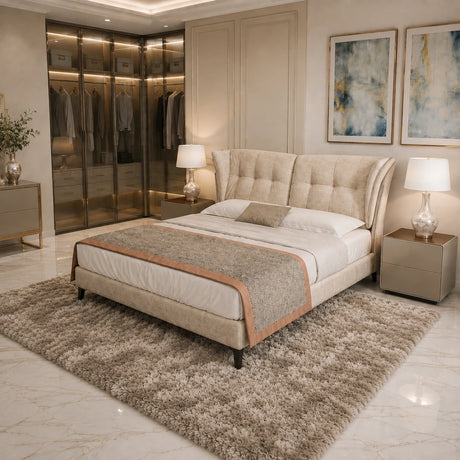 A luxury upholstered bed in a modern, elegantly decorated bedroom. The bed features a tufted beige wingback headboard and matching footboard, dressed in white linens with a textured beige throw blanket.