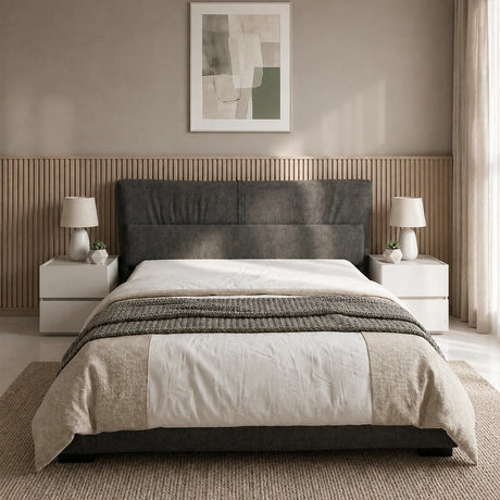 A modern bed with a dark gray upholstered headboard, dressed in white and beige bedding, set in a minimalist bedroom with a slatted wood headboard panel, bedside tables, lamps, and a textured rug.